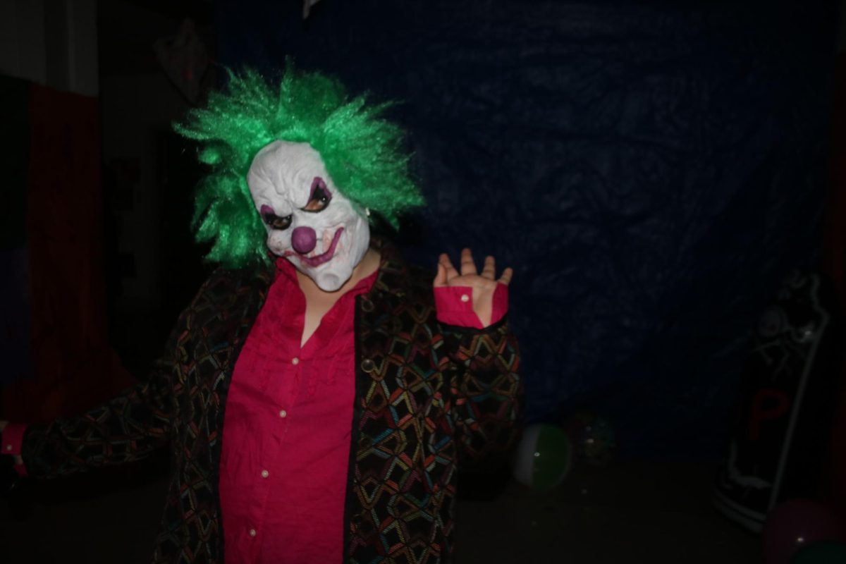 A parent volunteer in costume as a clown poses for the camera October 23rd, at Haunted Halls on the Hill.