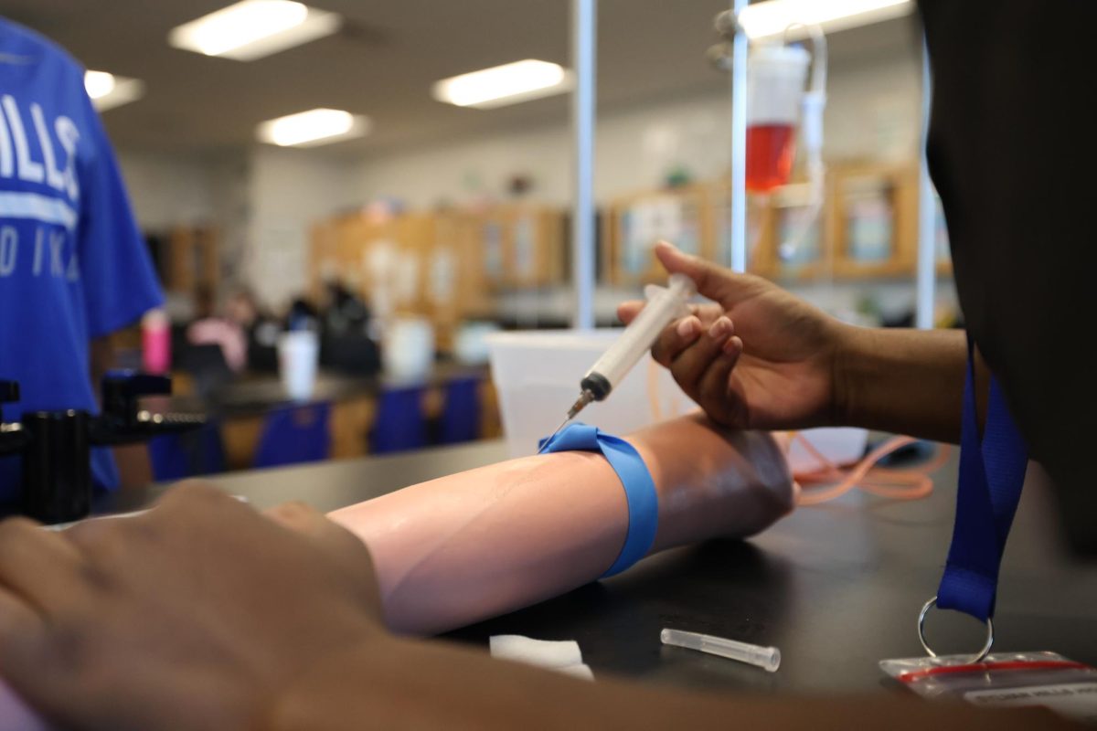 Eryn Egar (10) drawing blood on phlebotomy arm. 