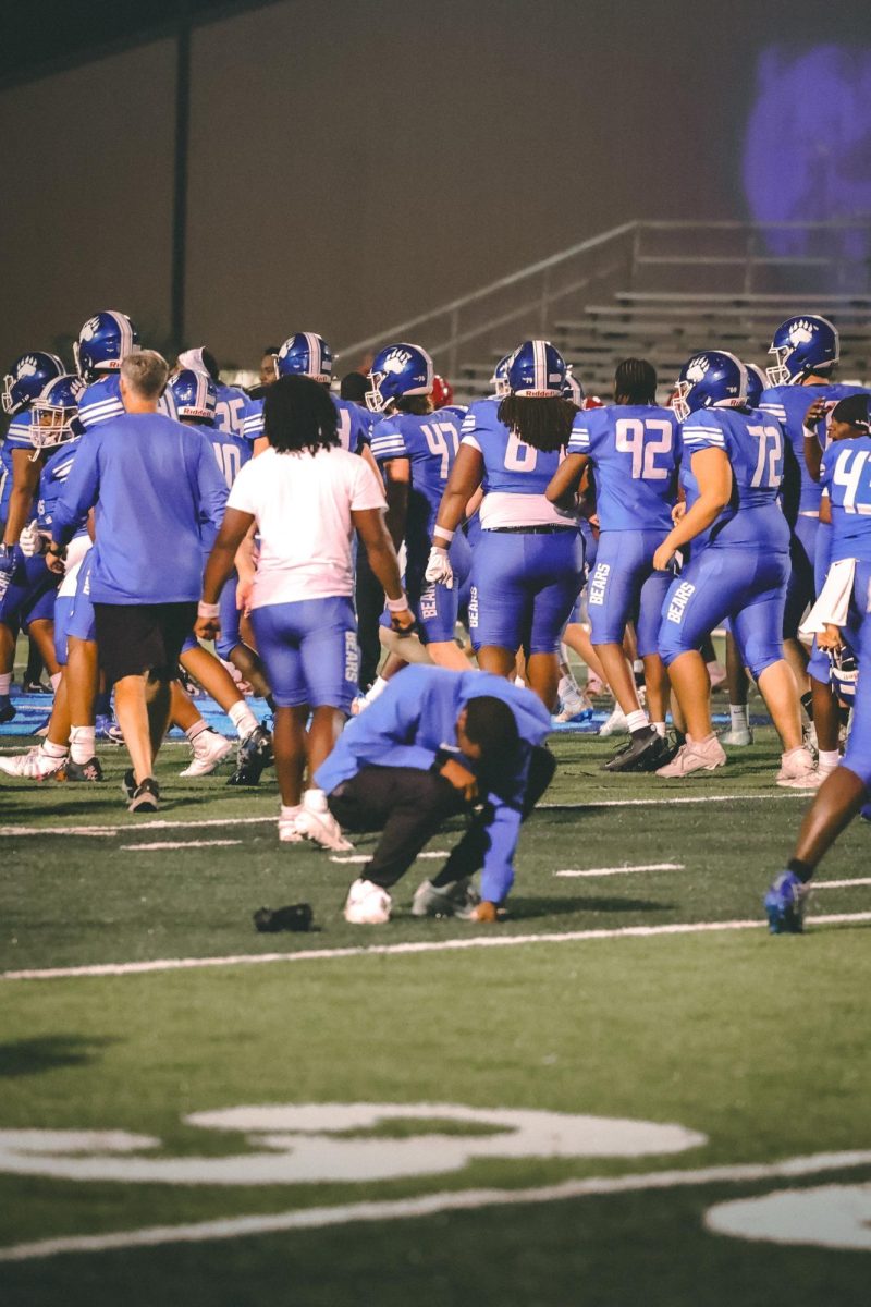 As the bears huddle together after their  win against Maumelle, Coach Roman kneels to the ground in glory of the amazing moment.