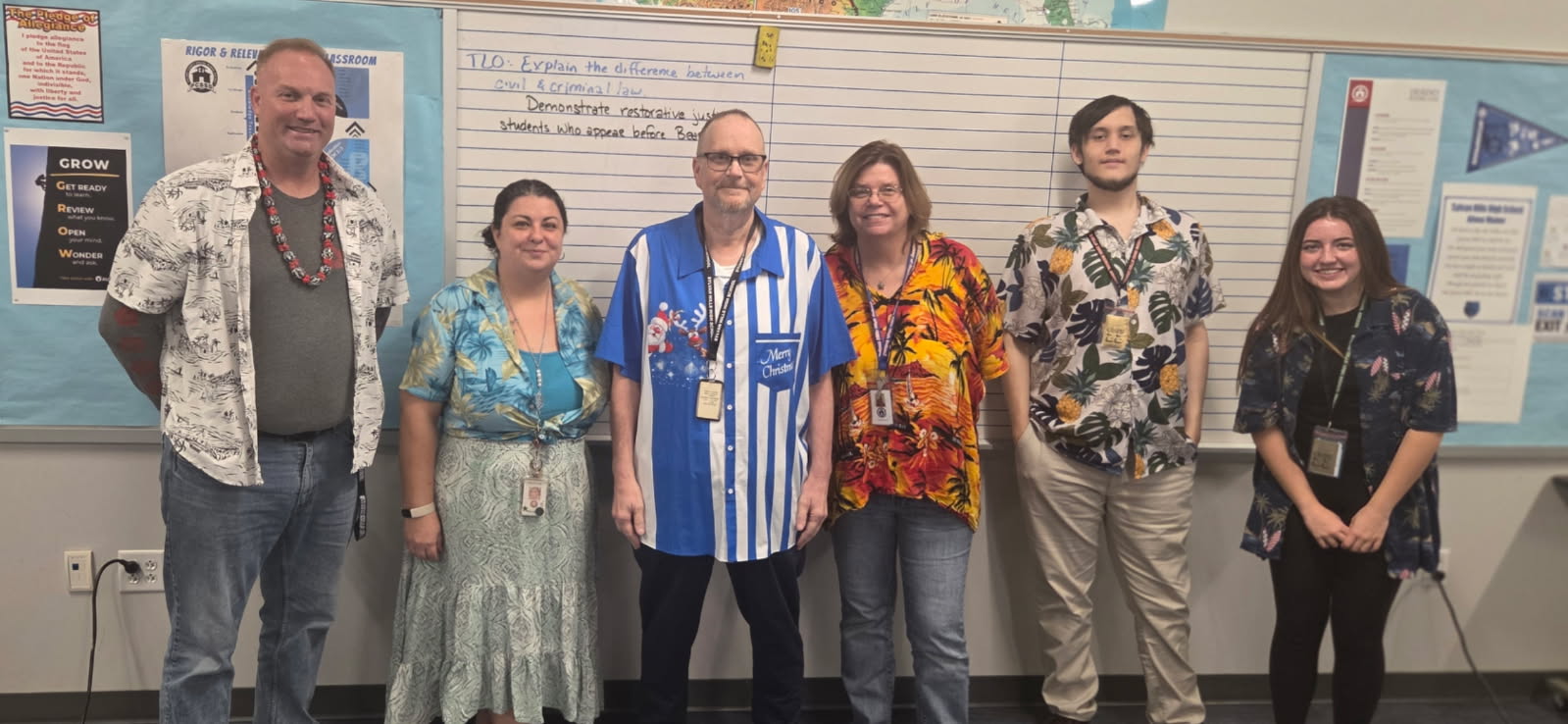 Mr. Harper, Ms. Cole, Mr. Romaine, Ms. Whisnant, Ian Cook (12), and Haley Belin (12) gather in Mr. Harper's room to enjoy Hawaiian shirt Day. Mr. Romaine, known for his festive shirts, made the special trip to surprise everyone.