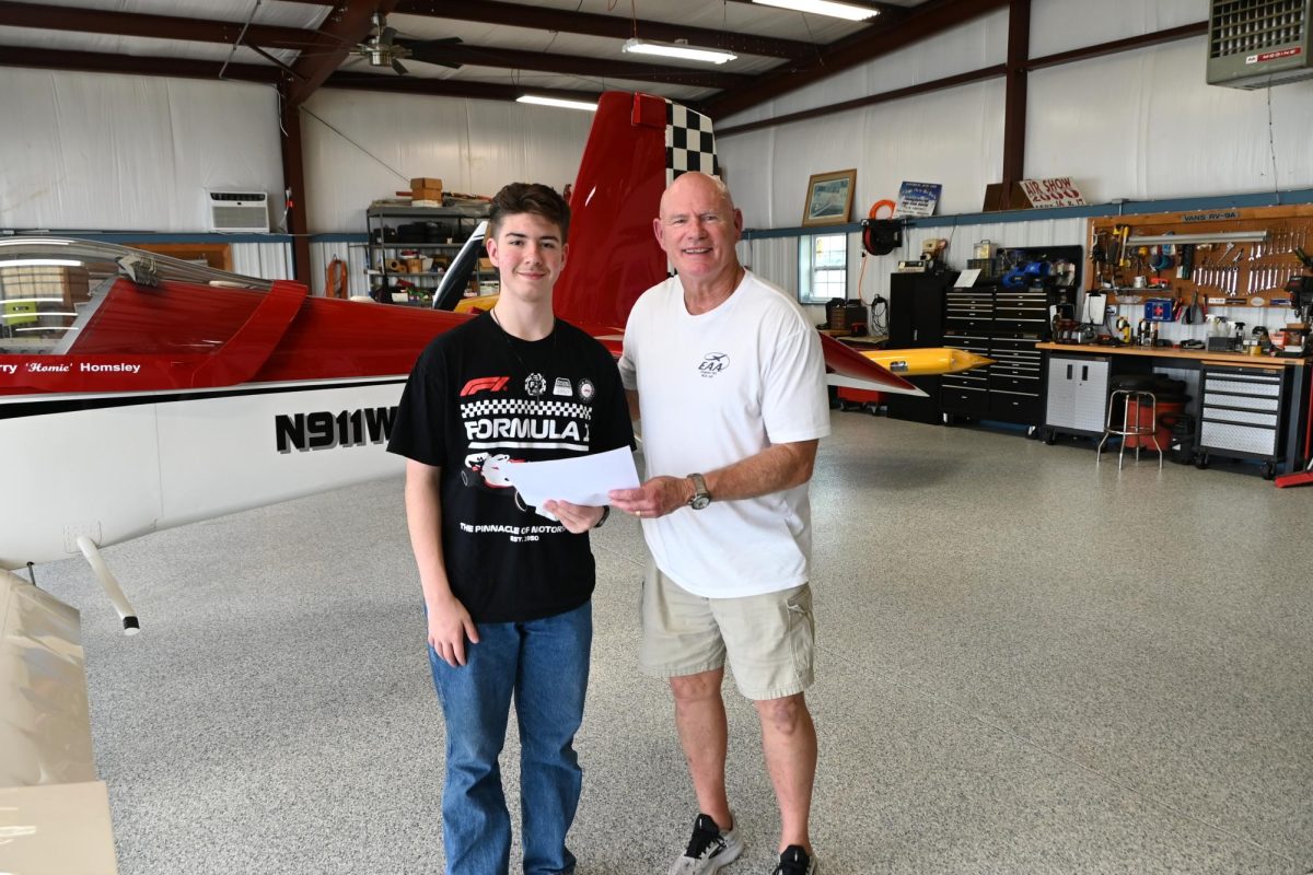 Sophomore Liam Fisher poses with Mr. Greg, a volunteer EAA pilot, as Liam is presented his flight certificate. 
